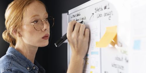 web-designer-feminina-com-papeis-e-notas-no-escritorio